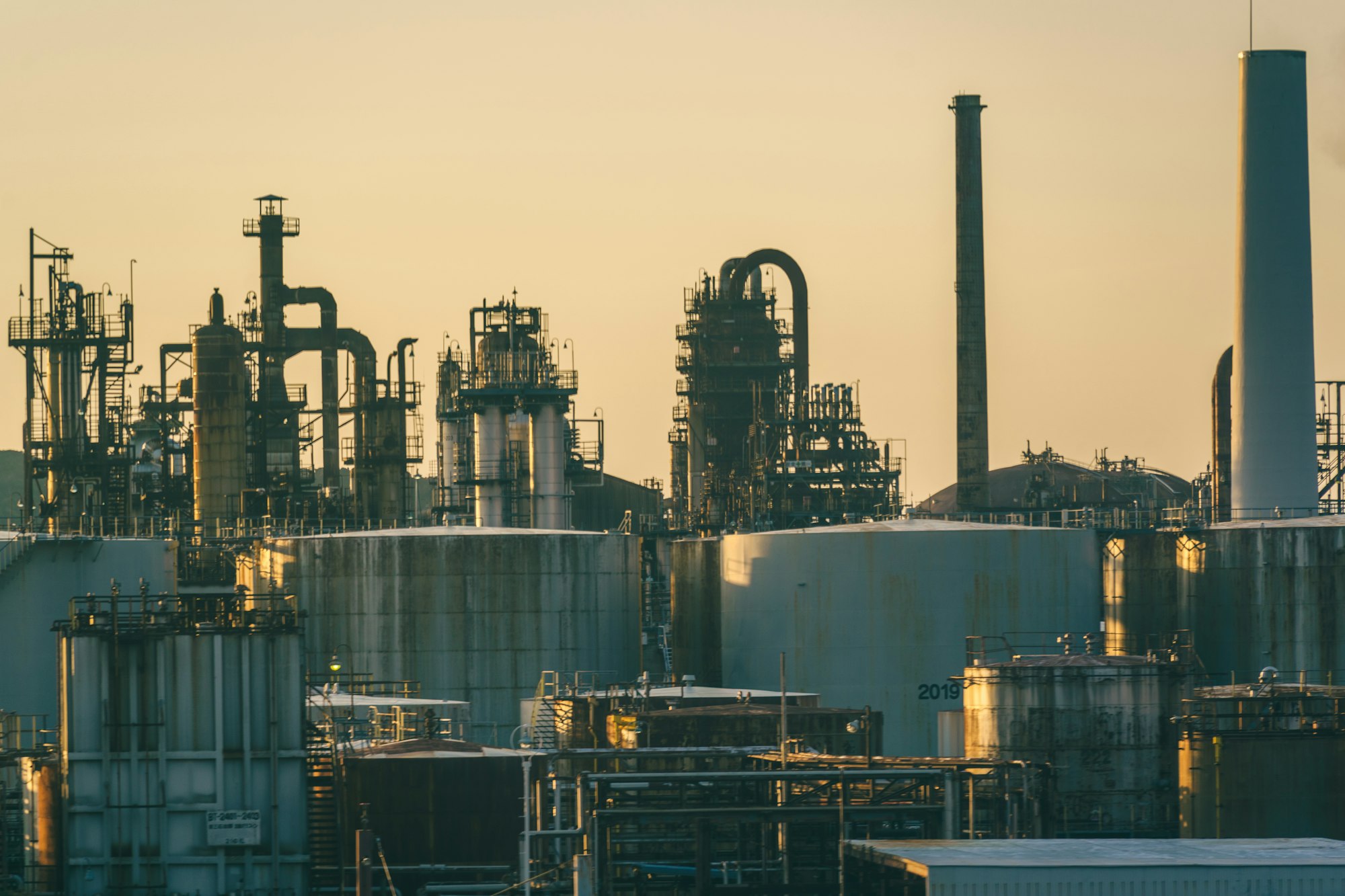 Industrial storage tanks and processing towers at sunset